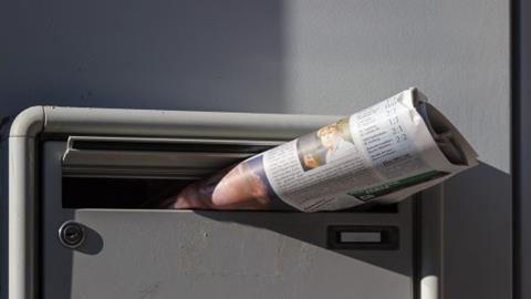 newspaper posted through a letter box